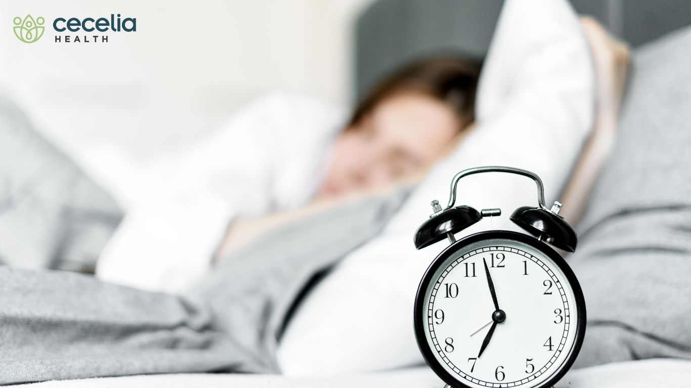 woman sleeping in bed with alarm clock in foreground