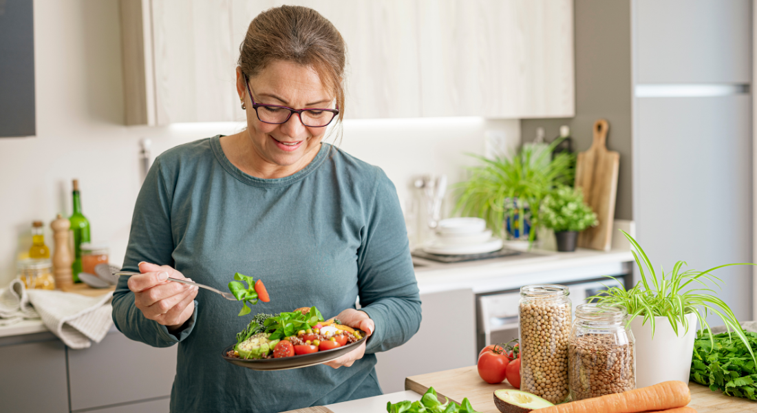 woman eating healthy salad in kitchen