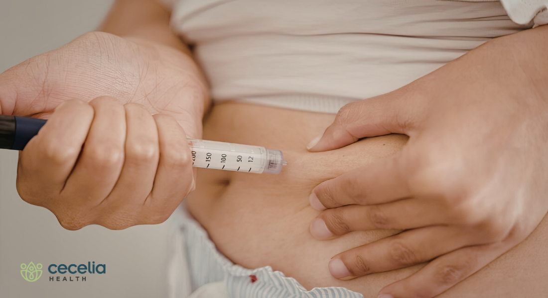 person injecting insulin needle into stomach