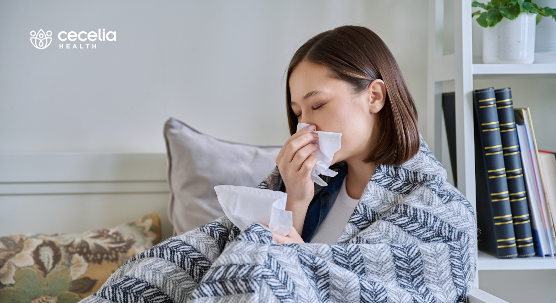 woman sitting under a blanket with a cold
