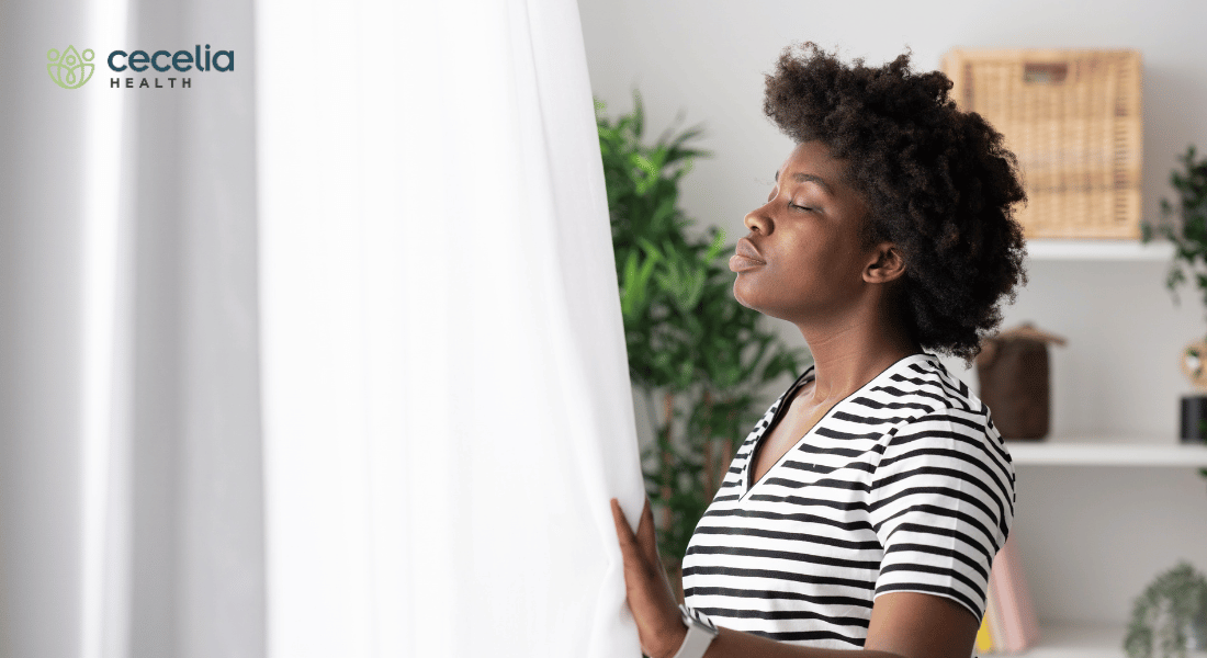 woman looking out window taking deep breath