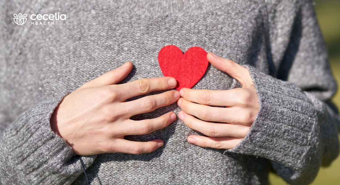 woman holding small paper heart next to her chest