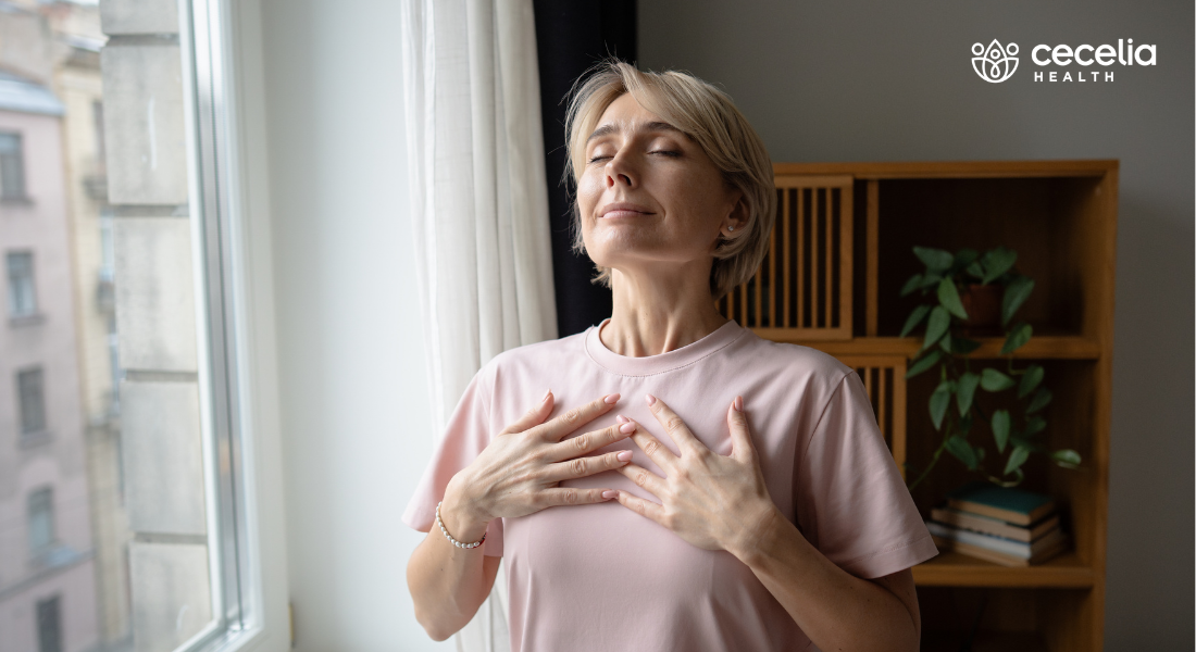 woman standing near window taking deep breath