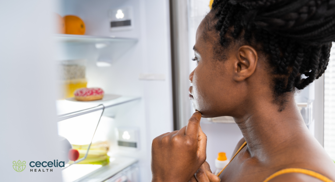woman standing in front of a fridge looking at food