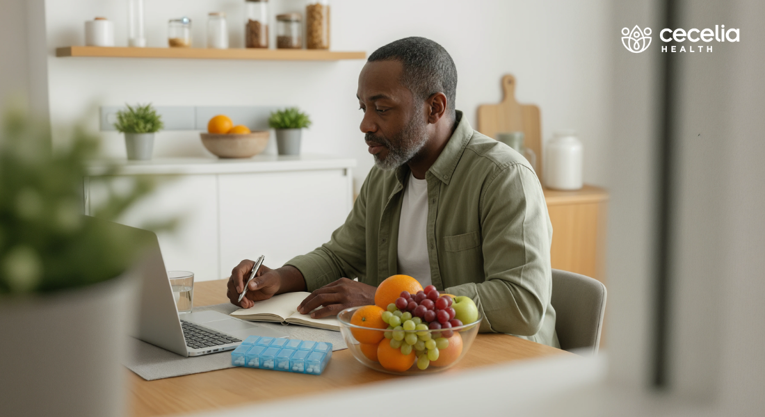 african american man taking notes at a computer next to pill organizer and food bowl