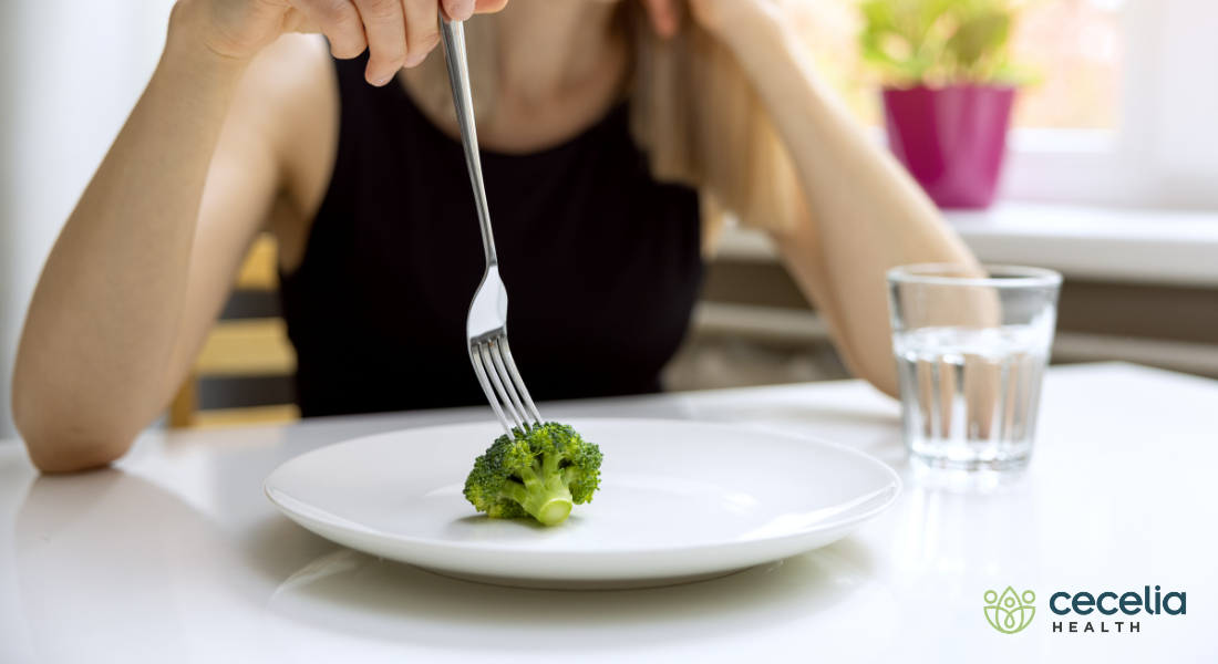 woman eating piece of broccoli
